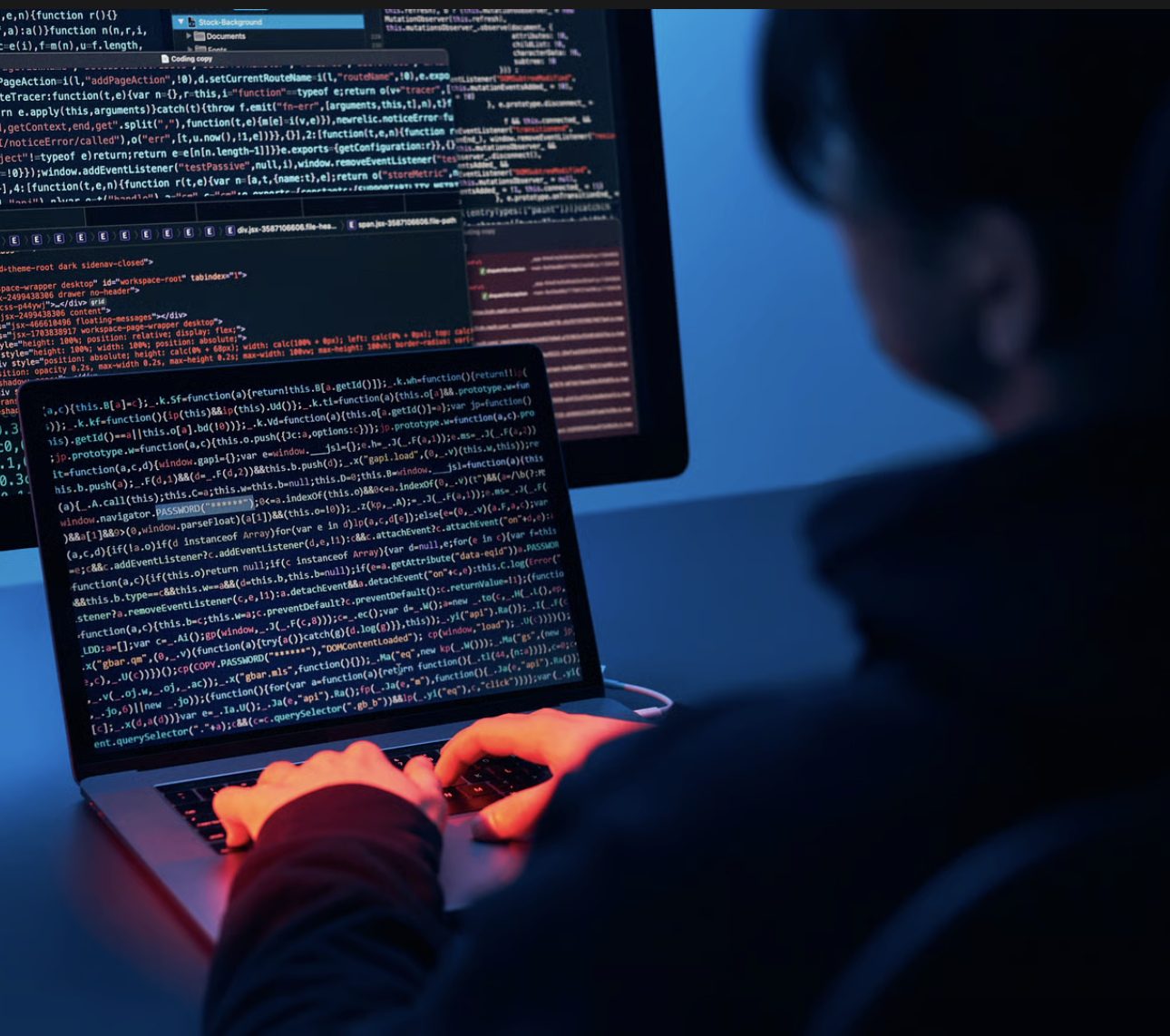 Hands typing on a laptop lit in red
